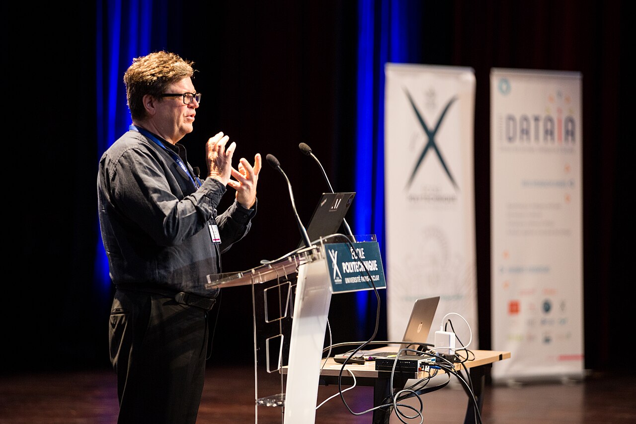 Yann LeCun speaking at a conference podium
