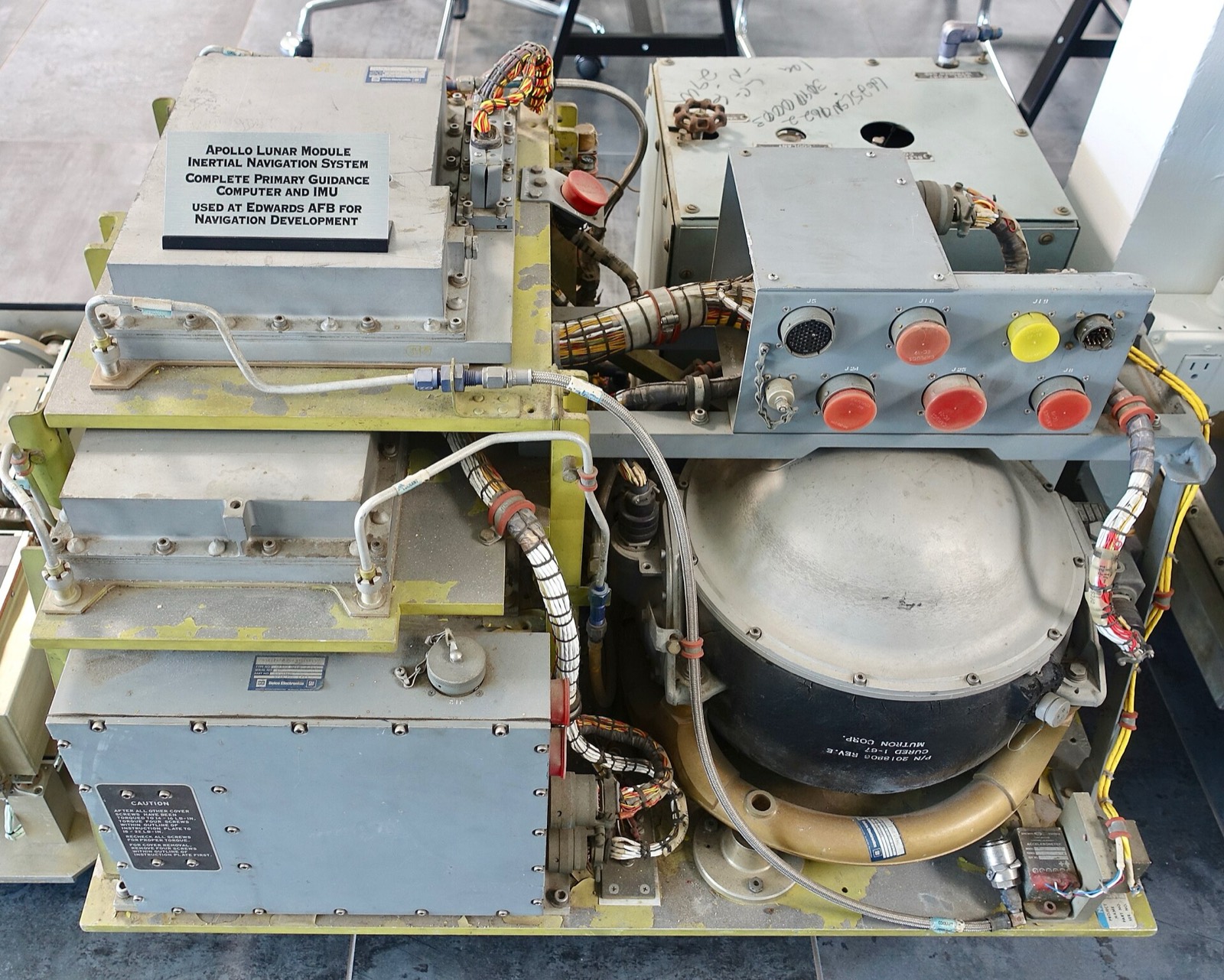 An Apollo Lunar Module inertial navigation system on display: a primary guidance computer and gyroscope unit, with cables and grey metal housings.