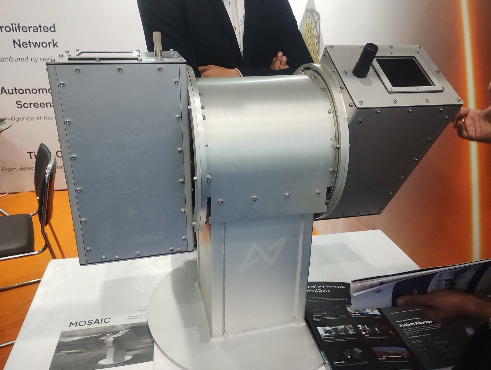 A grey metal optical sensor unit on a pedestal at Digantara’s exhibition stand.
