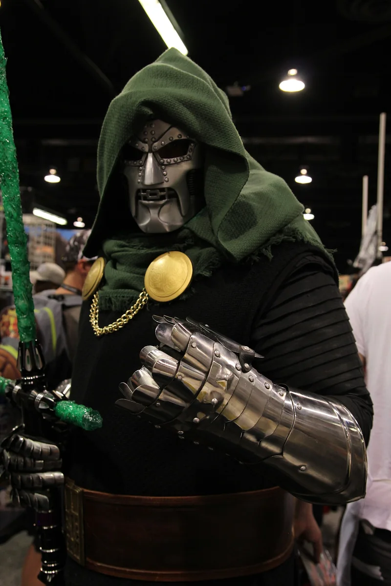 A Doctor Doom cosplayer in a green hood and articulated silver gauntlets.
