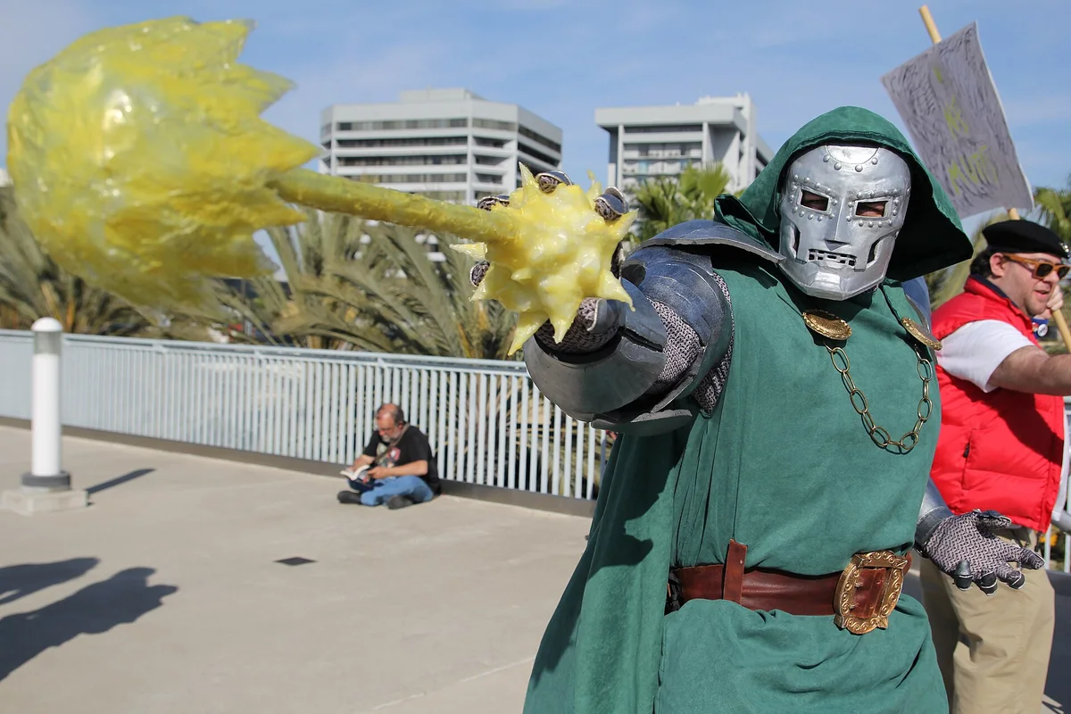 Doctor Doom cosplay: a silver mask, a green hood and an extended gauntlet with a yellow sorcery effect.