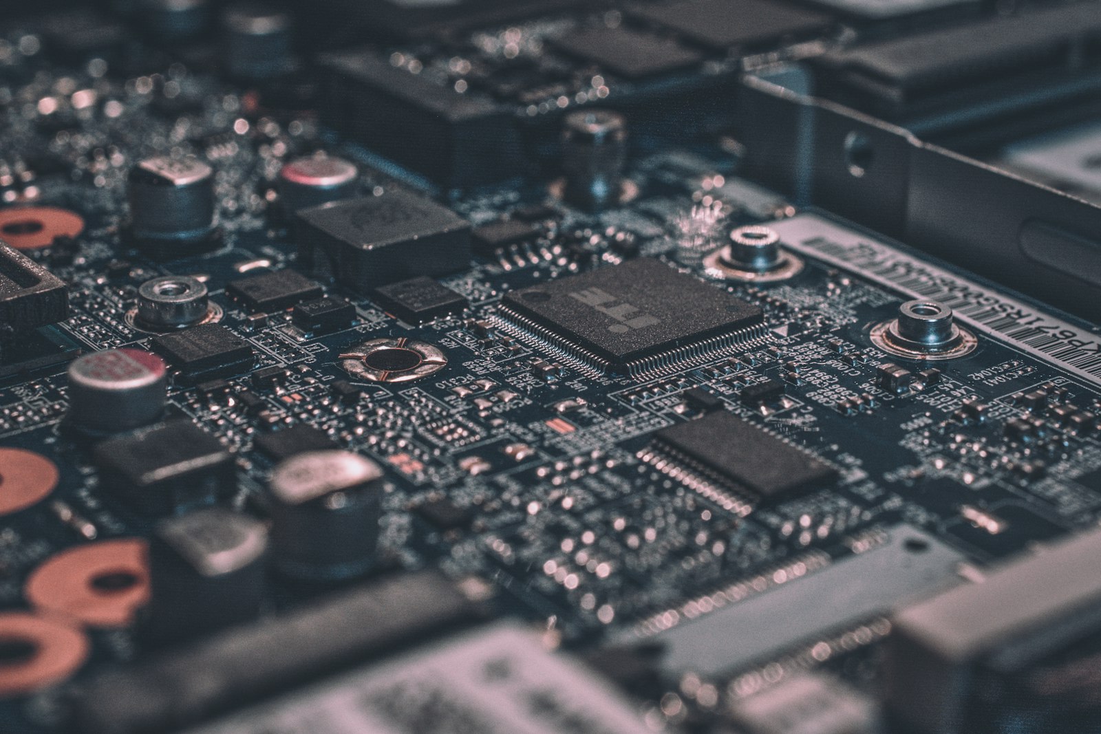 A green printed circuit board in low light, a processor and components picked out by a single highlight
