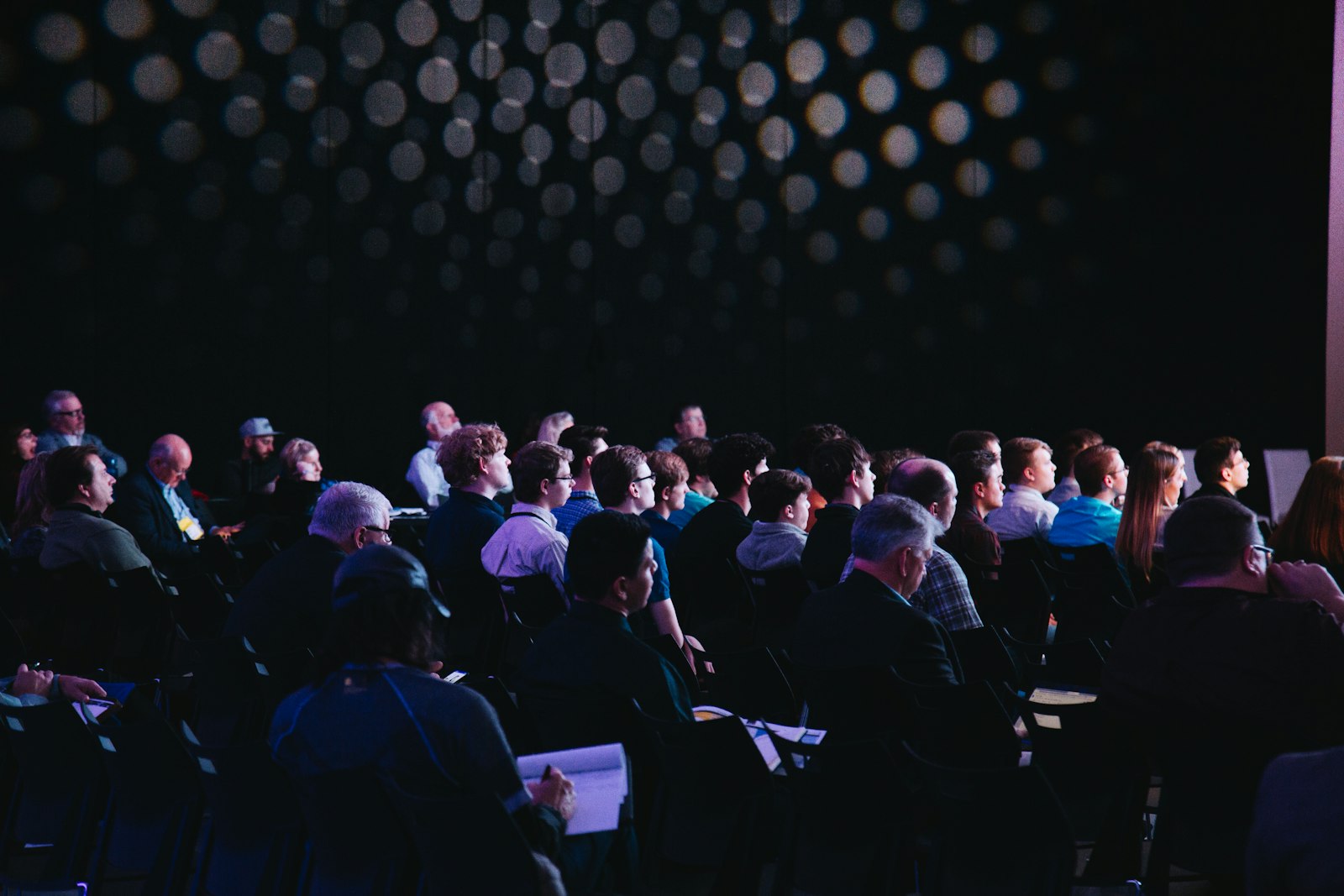 A dark auditorium full of seated founders and CTOs, their faces lit by a stage out of frame