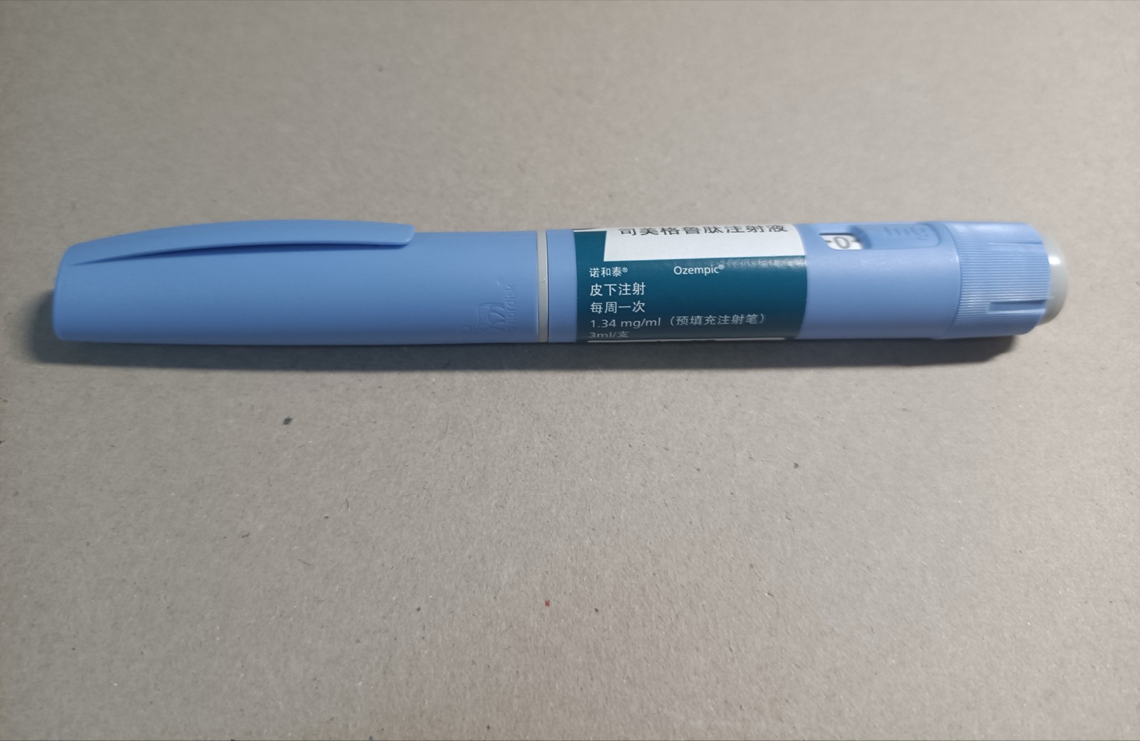 A GLP-1 medication injection pen lying on a plain surface.