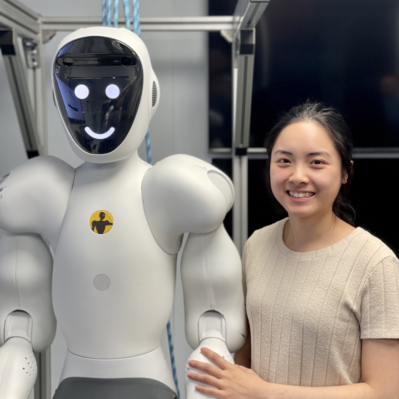 An engineer standing beside a full-size humanoid robot in a workshop.