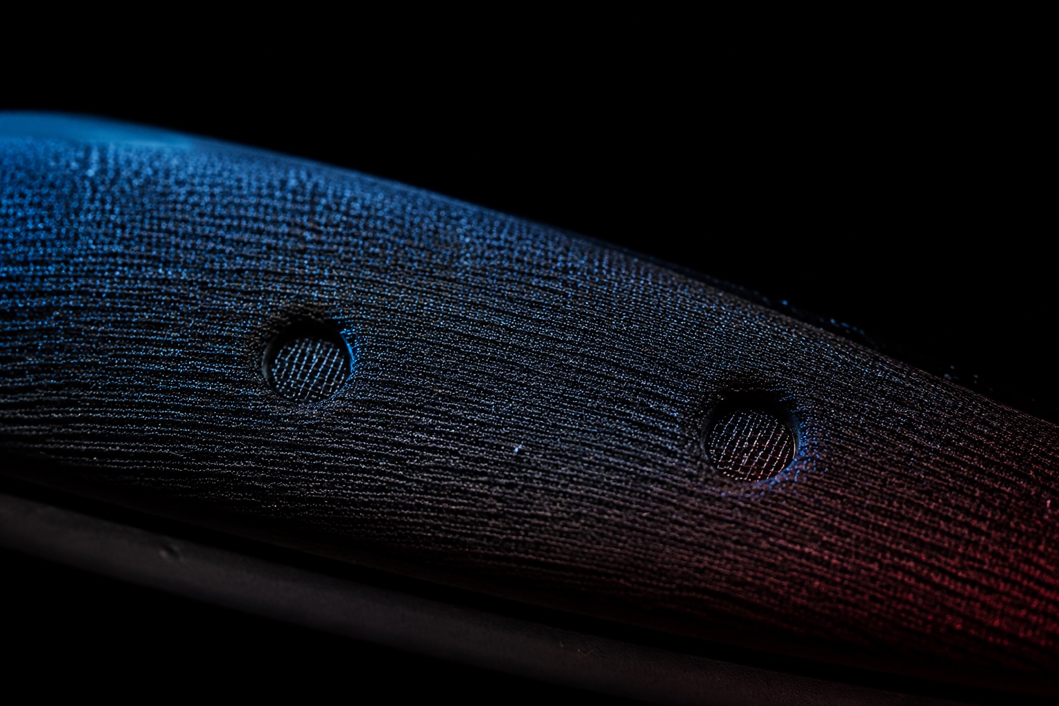 An imagined macro view of two microphone ports behind textured black acoustic mesh